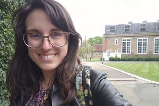 Brunette woman with glasses, smiling to the camera.