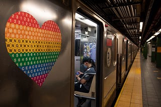 A pride colored heart is seen on a subway car near a person wearing a mask as the city moves into Phase 2 of re-opening following restrictions imposed to curb the coronavirus pandemic on June 25, 2020 in New York City.