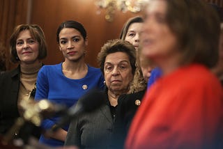 U.S. Reps Alexandria Ocasio-Cortez, Kathy Castor, and Donna Shalala listen as  Speaker of the House Nancy Pelosi speaks.