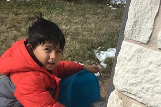 A child collecting water from a gutter downspout in Texas