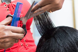 A closeup photo of a hair stylist cutting a client’s hair.