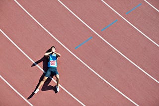 A tired runner lies down on a track.