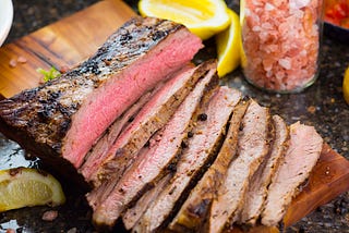 Flank steak sliced on a board.