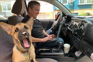 American Giant CEO Bayard Winthrop working on his laptop out of his truck with his 3-month-old puppy.