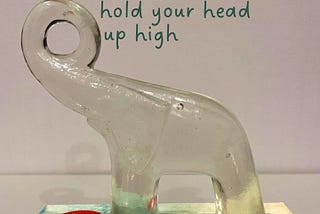 An glass elephant figurine on top of Marie Kondo’s book, ‘The Life Changing Magic of Tidying Up’. The phrases, ‘hold you head up high’ and ‘stand your ground’ are superimposed on the image.