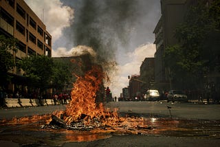 A junk pile on fire in the middle of an empty city street