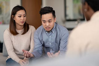 A married couple talks to a therapist together about their life. They are attentive and focused.