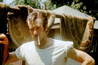 Man in white t-shirt smoking a cigarette.