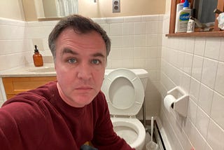 Matt Farley, a TikTok creator, poses for a selfie next to a toilet in his restroom.