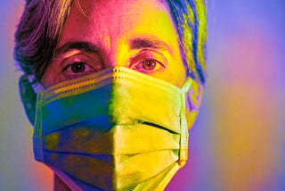 A multicolored closeup photo of a woman wearing a face mask.
