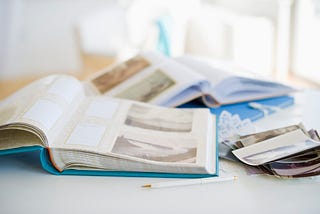A photo of two photo scrapbooks on a table with some polaroids on the side.