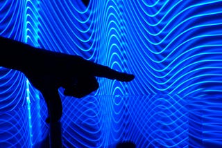 The silhouette of a hand pointing out something against a neon background.
