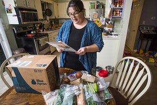 Emily Griffin reads a recipe for a Blue Apron meal while unpacking her box at her Lisbon Falls home.