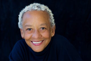 Portrait photo of Nikki Giovanni against a black background.