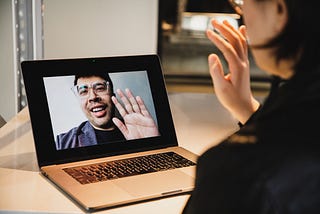 Remote job interview, woman waves to the interviewer through the webcam.