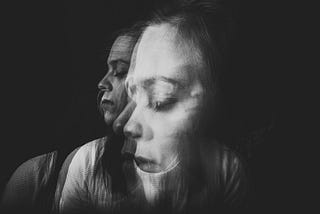 A black-and-white, triple-exposed photo of a woman with her eyes closed.