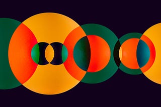 Green and orange circle spheres overlapping on solid dark background.