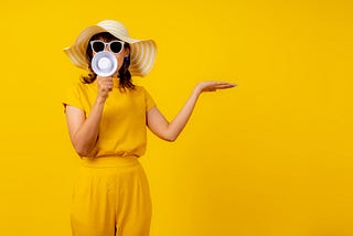 A lady with a handheld loudspeaker against a yellow background
