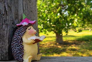 A hedgehog statue reading under a tree