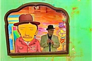 Photograph of myself reflected in a Mirror taking a picture of myself in the mirror with a cartoonish head next to me on a very surreal and dismal wall with strange objects mounted on it in a very cartoonish looking atmosphere