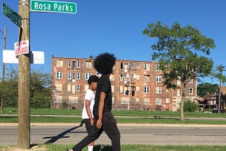 A photo of two Black youths walking down a street in Detroit.