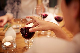 Woman holding a wine glass filled with red wine.