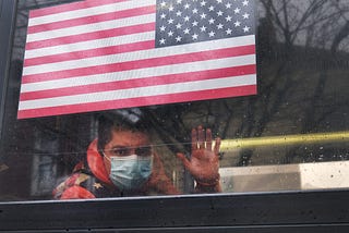 A man waves from a bus in a neighborhood in the Queens borough, which has one of the highest infection rates of coronavirus.