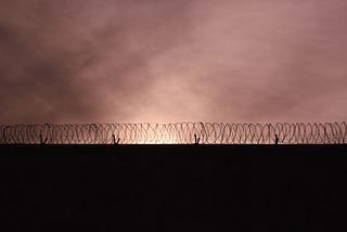 A photo of a barbed wire fence against a sunset sky.