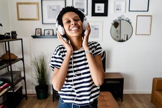 Black woman listening to music on headphones at home.