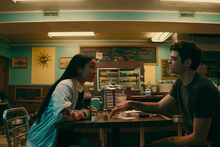 A photo still from the Netflix movie “To All the Boys I’ve Loved Before” that shows Lara Jean and Peter at a diner.