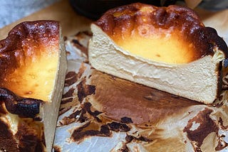 A halved basque cheesecake in a small custard tin,