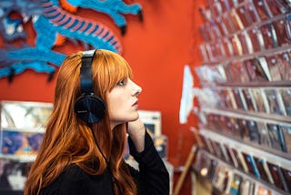 A woman is shopping for records while listening to music.