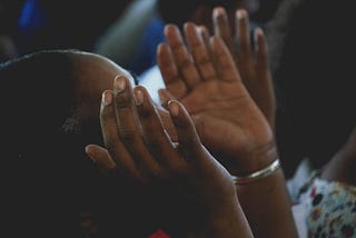 Black woman raising her hands in prayer.