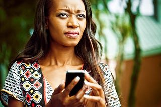 A photo of an annoyed black woman on her phone.