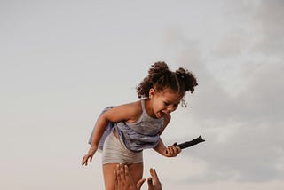 A child is thrown in the air by their father at a beach