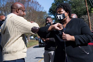 Reverend Raphael Warnock and Stacey Abrams bump elbows.