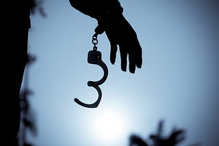 A photo of handcuffs being uncuffed on a person’s hand.