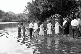 Mid-century children wade into the local river for a group baptism.