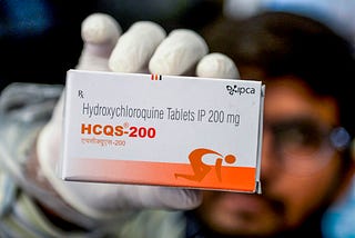 A pharmacist displays a box of hydroxychloroquine tablets.
