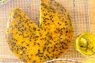 A yellow/orange passion fruit curd with flecks of black seeds and a jar full of the sweet stuff with a spoon dipped in it