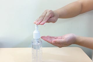 A photo of a person squirting hand sanitizer out of a bottle onto their hands.