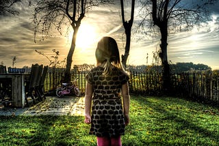 Young girl in backyard gazing into sunrise