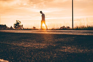 Walking along a stretch of road, by the sunset.