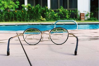 looking at a pool from a round lenses glasees in a summer atmosphere, vegetation in the background