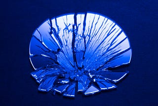 A blue-tinted photo of a shattered mirror.