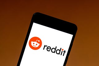 A photo illustration of the Reddit logo, displayed on a mobile phone.