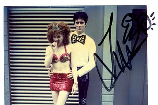 Signed polaroid of The Cramps on city street, dressed to kill.