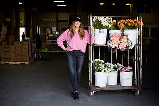 Christina Stembel stands next to various flowers in their warehouse.