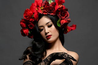 A woman wearing an Indonesian Bunga Mawar hair design poses in a black dress.