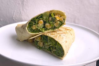 Chickpeas and lettuce shimmering with a creamy caesar dressing, stuffed into a large tortilla folded wrap-style.